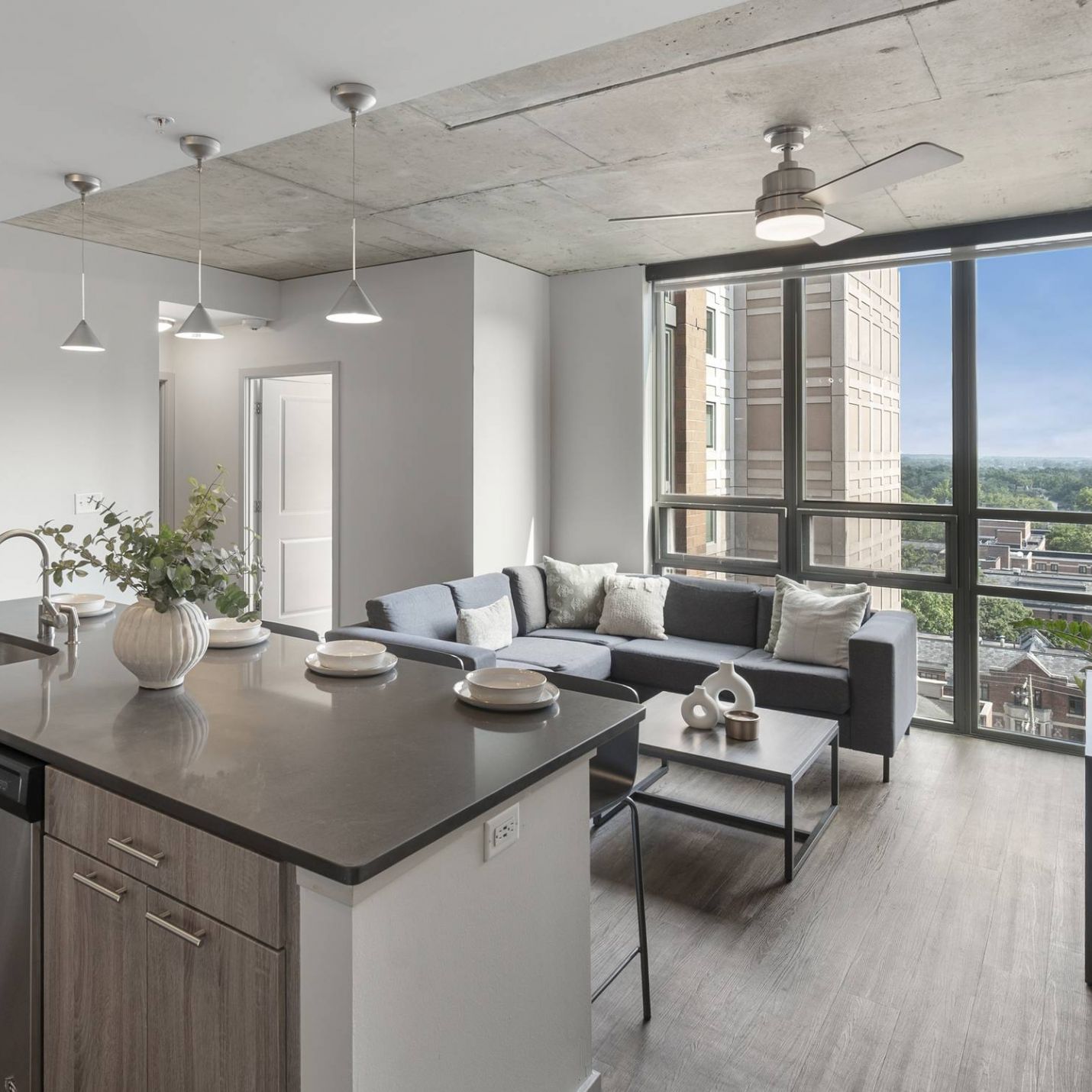 Six11 Student Living Apartments Modern apartment with a kitchen island, living area, large window, and city view.