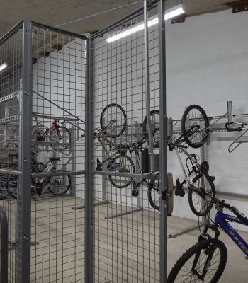 Six11 Student Living Apartments Indoor bike storage room with metal fencing and bikes hanging vertically on wall racks.