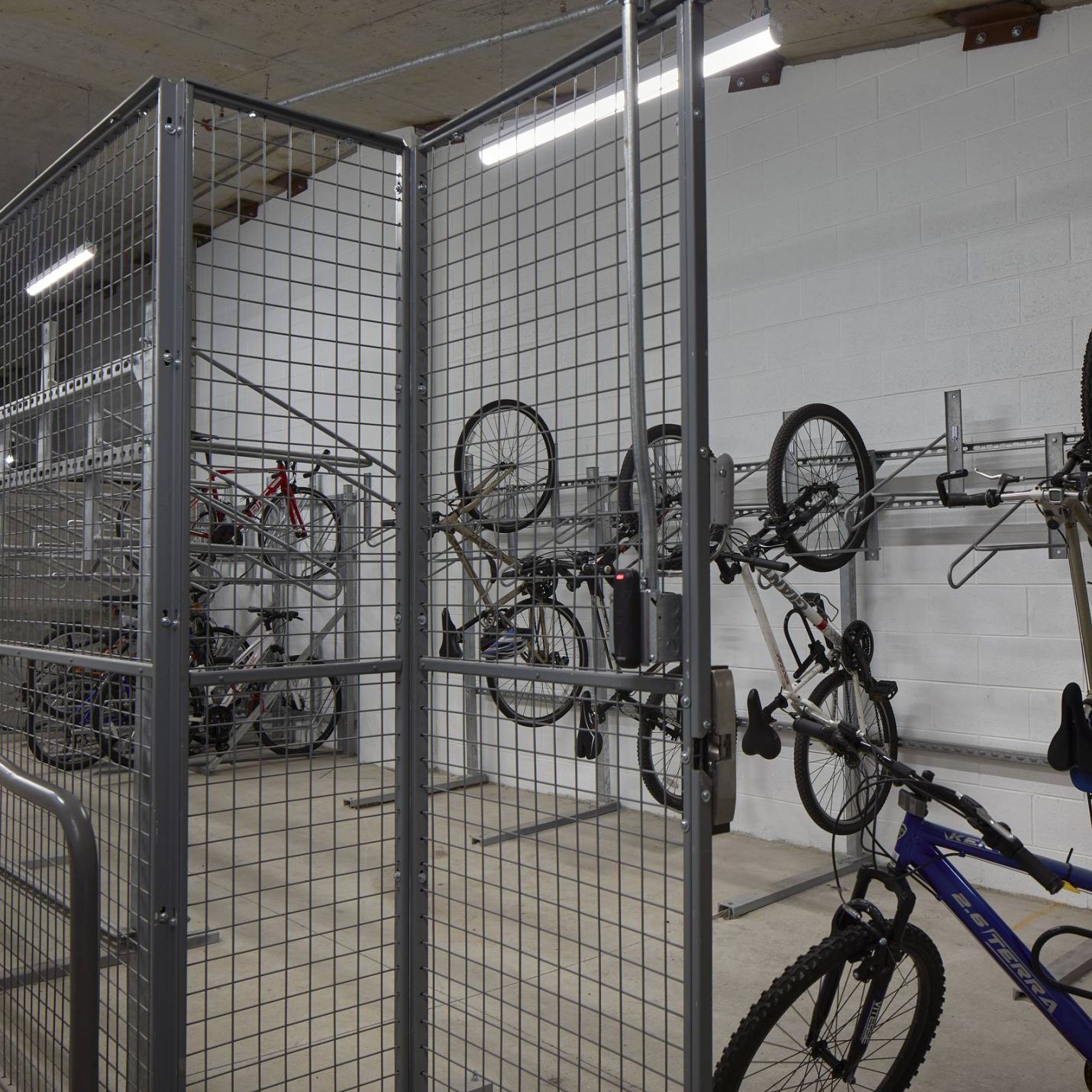 Six11 Student Living Apartments Indoor bike storage room with metal fencing and bikes hanging vertically on wall racks.