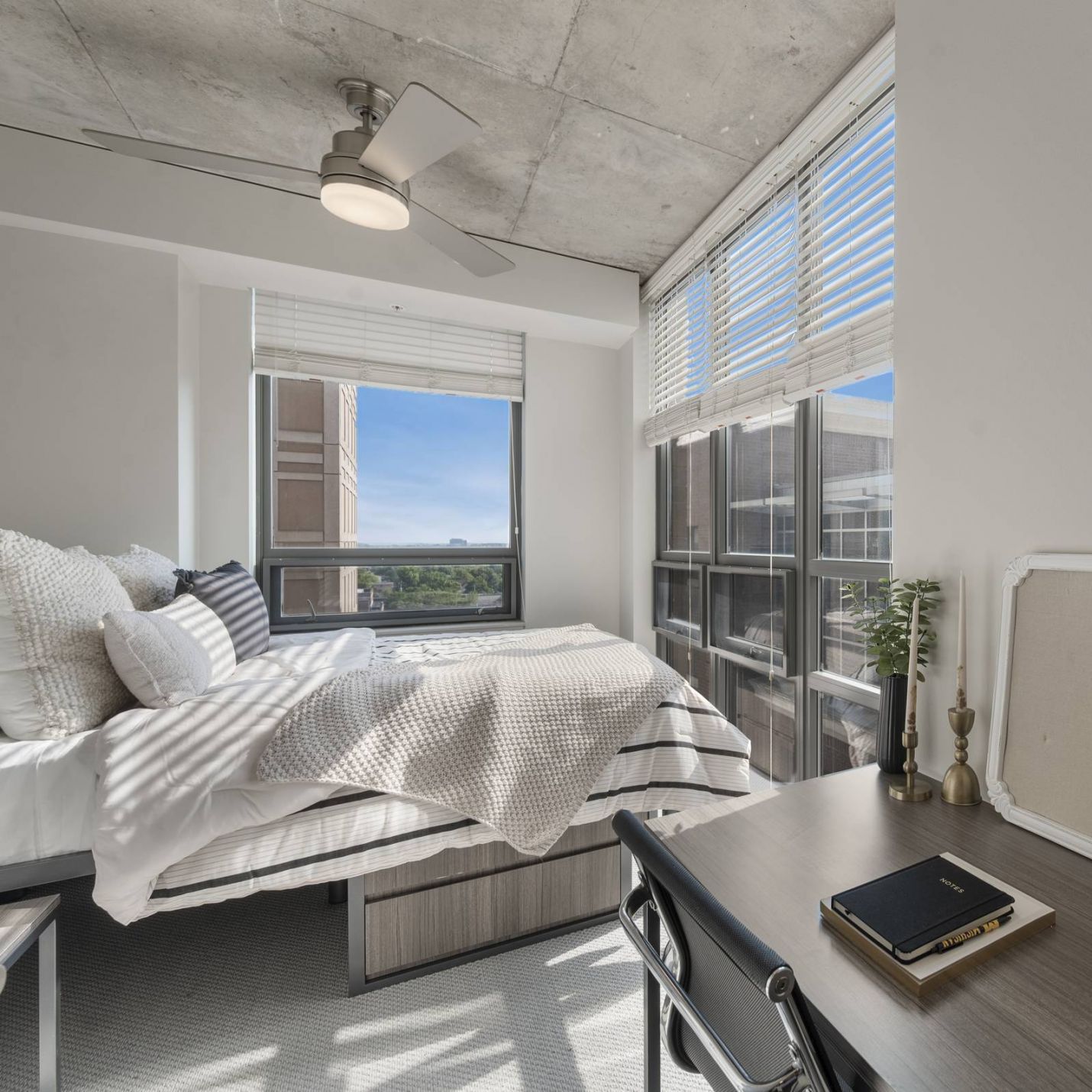 Six11 Student Living Apartments Bright bedroom with large windows, a bed, a desk with a globe, and modern decor, filled with natural light.