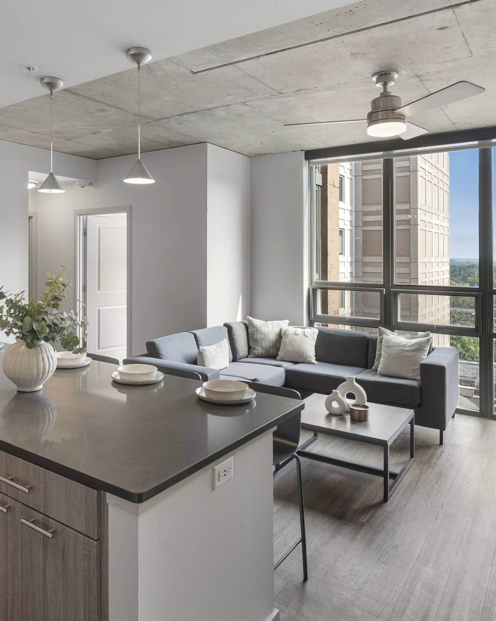 Six11 Student Living Apartments Modern apartment with a kitchen island, living area, large window, and city view.