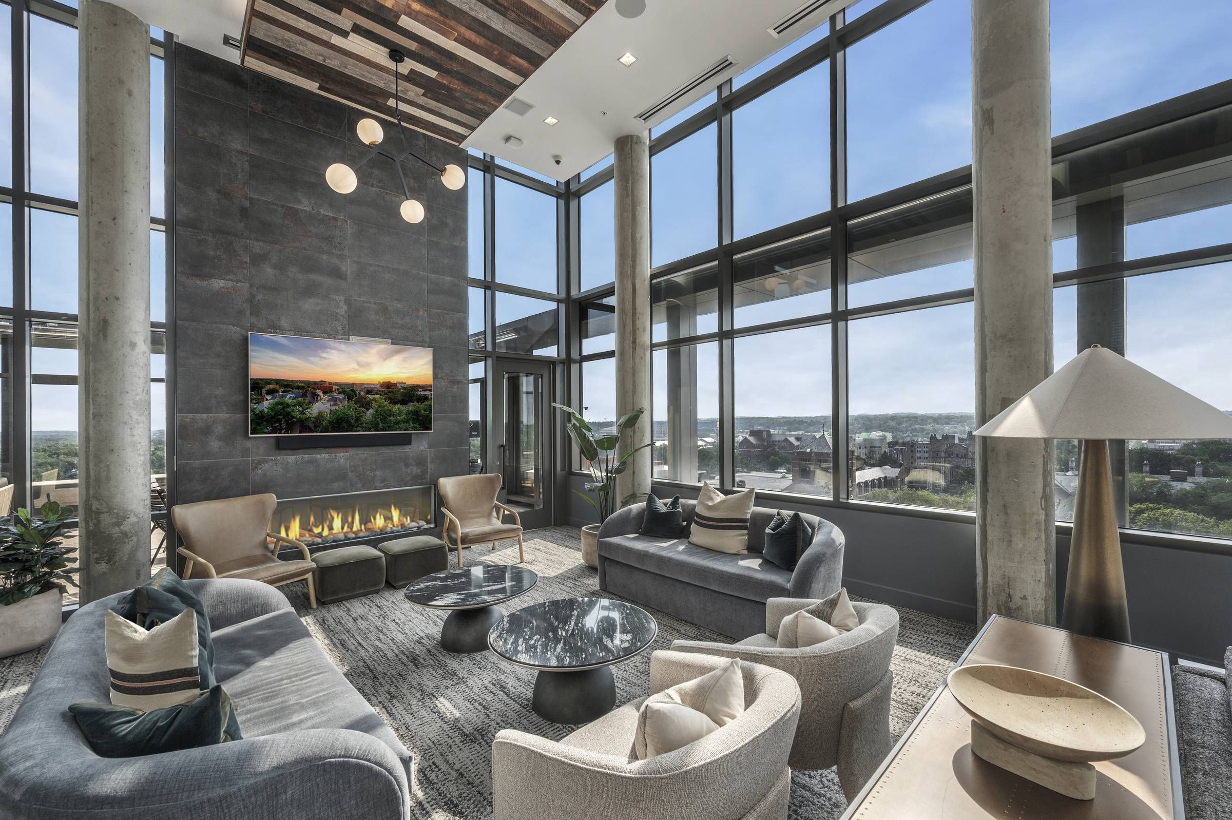 Six11 Student Living Apartments Modern living room with large windows, contemporary furniture, fireplace, TV, and city view.