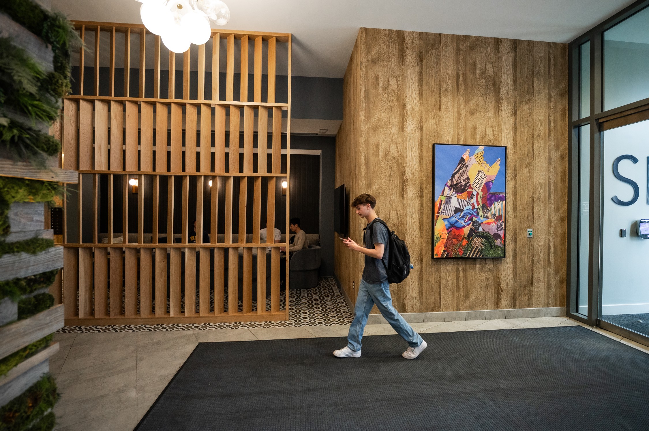 Young man walking into the lobby of Six11 student apartments