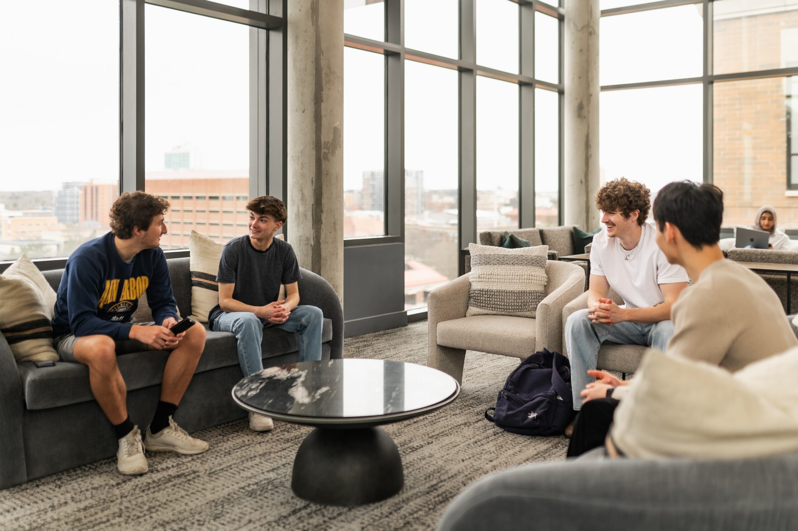 Six11 residents hanging out in the study lounge with downtown Ann Arbor views