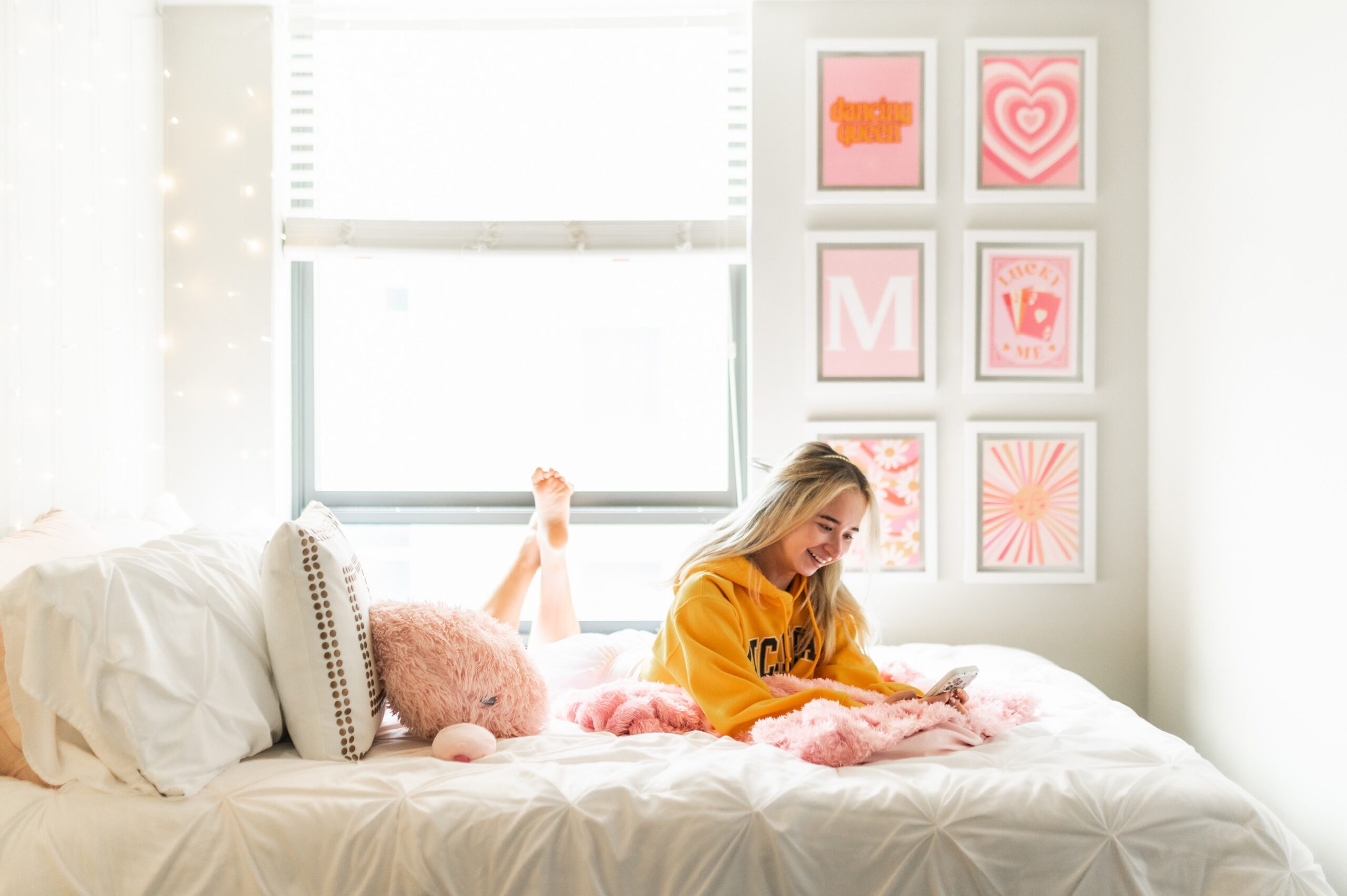 Young woman playing on her phone in her bright bedroom at Six11