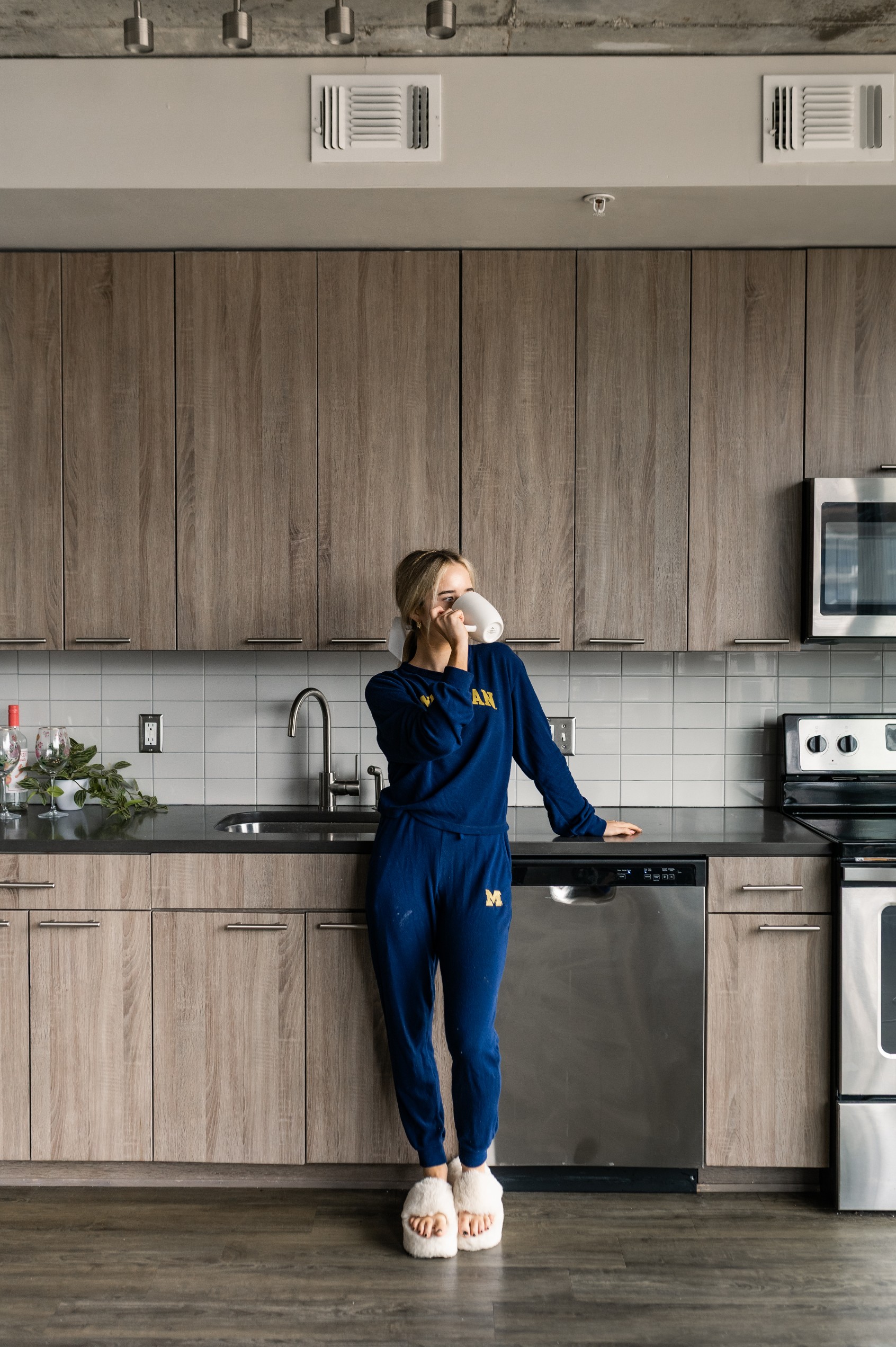 Young woman drinking coffee in the stylish kitchen of her student apartment at Six11