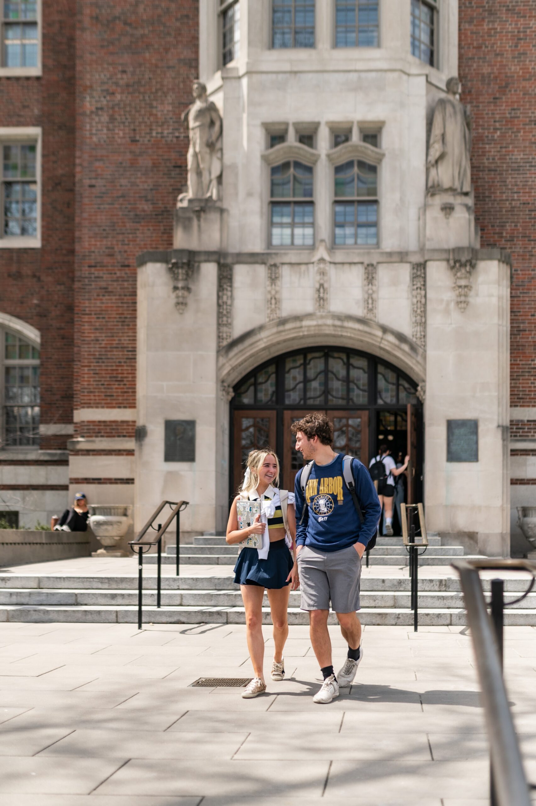 Boy and girl walking out of a historic building on the University of Michigan campus